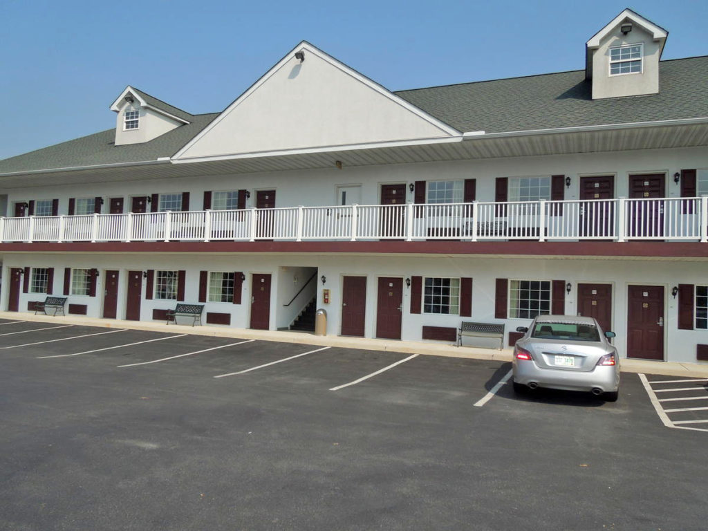 Two story building with exterior room entrances and walkways, parking spaces