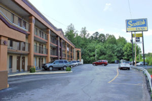 3 story building with exterior room entrances, covered walkways and stairs, brand signage, parking spaces