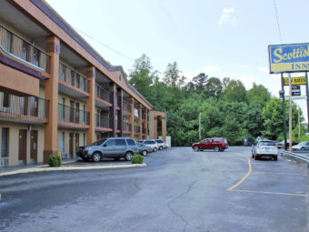 3 story building with exterior room entrances, covered walkways and stairs, brand signage, parking spaces