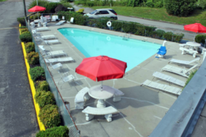 Outdoor pool with concrete surround, sun loungers, chairs, patio tables with benches and umbrellas, pool lift,
