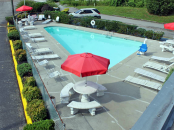 Outdoor pool with concrete surround, sun loungers, chairs, patio tables with benches and umbrellas, pool lift,