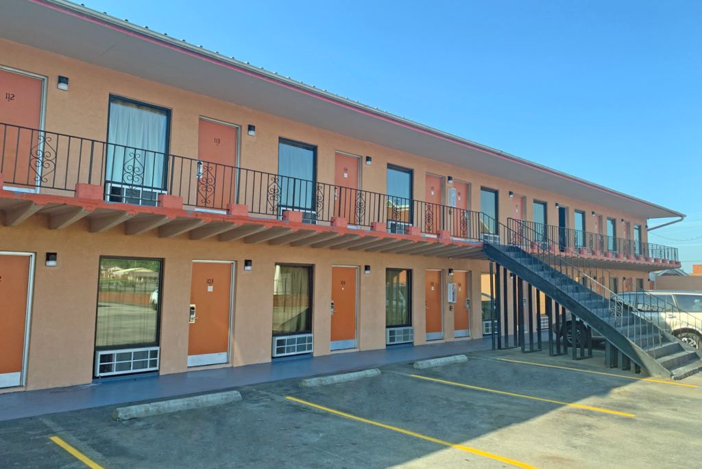 STNMO Exterior 200 Two story building with exterior room entrances, covered walkways and stairs, parking spaces