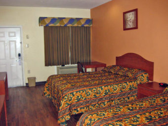 Two queen beds, night stand with clock, wall mounted art, small table and chair, laminate flooring