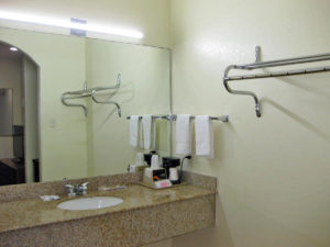 Vanity unit with coffee maker, wall mounted mirror with overhead strip light, wall mounted hanging rail and towel rail with towels