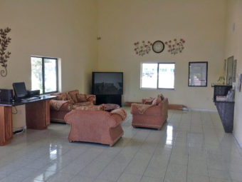 Guest check in desk, sofas, easy chairrs, flat screen tv, occasional table, desk with cumputeer monitor and printer, clock wall decor, tiled flooring