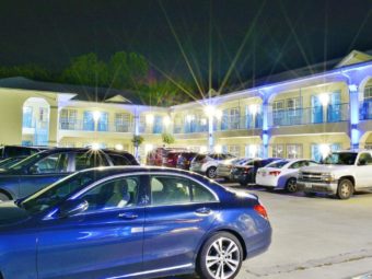 Two story building displayed at night with exterior room entrances, walkways and stairs, parking spaces