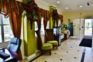 Desk with office chair. occasional chairs, aquarium. floral wall decorations, door way to guest information leaflet stand and ice machine, tiled flooring