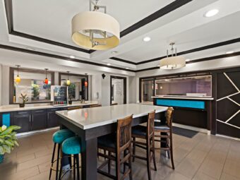 Breakfast display counter with fridge, planter with plants, high level table with chairs and stools, guest check in desk, tiled flooring