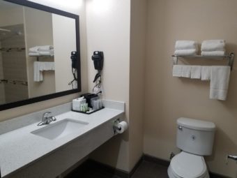 Vanity unit, wall mounted hairdryer, wall mounted twoel rail with towels, wall mounted mirror, toilet, tiled flooring