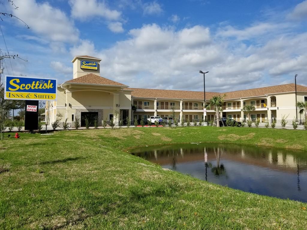Two story building, brand signage, parking spaces, grassy area with pond