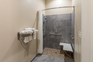 Shower with shower curtain, shower seat, grab handles, towel rails and shelves with towels