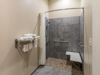 Shower with shower curtain, shower seat, grab handles, towel rails and shelves with towels