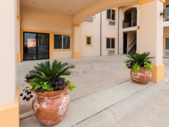 Hotel entrances, two story building with exterior entrances to rooms, covered walkways and stairs, potted plants, parking spaces