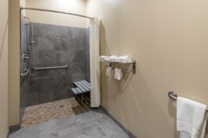 Walk in shower with shower curtain, seat and grab handles, towel rail with towels