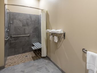 Walk in shower with shower curtain, seat and grab handles, towel rail with towels