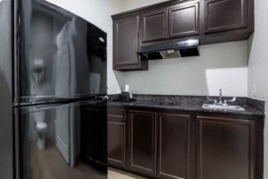 kitchenette with base and wall cabinets, sink and hob, fridge