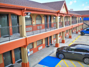 Two story building with exterior walkways and room entrances, parking spaces