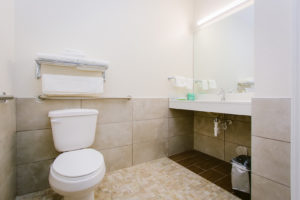 Toilet, towel rail and shelf with towels, vanity unit, mirror, tiled flooring