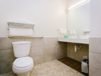 Toilet, towel rail and shelf with towels, vanity unit, mirror, tiled flooring