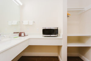 Vanity unit, mirror, strip light, microwave, alcove with hanging rail and shelving