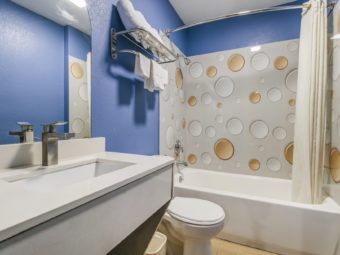 Sink, mirror, toilet, shelf and rail with towels, shower tub with shower curtain.