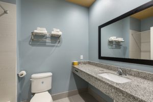 Vanity unit, mirror, towel rail and shelf with towels, toilet, tiled flooring