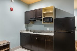 Base and wall cabinets, counter top with sink and hob, microwave, fridge
