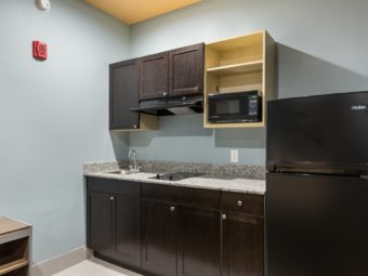 Base and wall cabinets, counter top with sink and hob, microwave, fridge