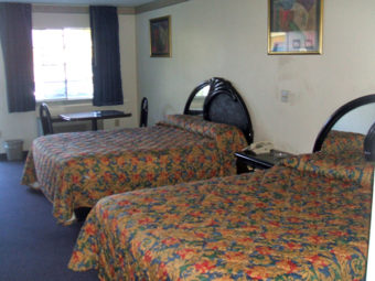 Two queen beds, night stand with telephone, small table and chairs, carpet flooring