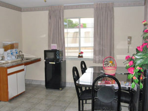 tables and chairs, breakfast display counter with cereal dispensers, fridge, microwave, tiled flooring