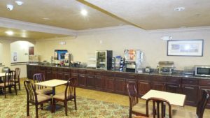 Breakfast display counter with cereal dispensers, juice dispenser, breakfast pastries display case, microwave, tables and chairs