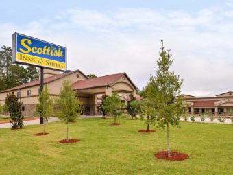 Two story and one story buildings, grassy area with small trees, brand signage, drive through canopy