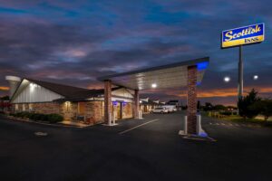 Brand signage, drive through canopy, hotel entrance, night time lighting, external entrances to guest rooms, parking spaces, landscaping with grassy areas and small bushes