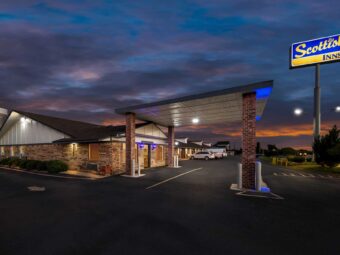 Brand signage, drive through canopy, hotel entrance, night time lighting, external entrances to guest rooms, parking spaces, landscaping with grassy areas and small bushes