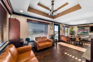Business center with computer, occasional table with flowers, sofas breakfast area with tables and chairs, laminate flooring