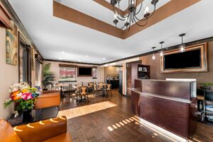 Guest check-in desk, occasional table with flowers, sofas breakfast area with tables and chairs, laminate flooring