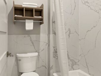 Toilet, shelves with towels, shower tub with shower curtain