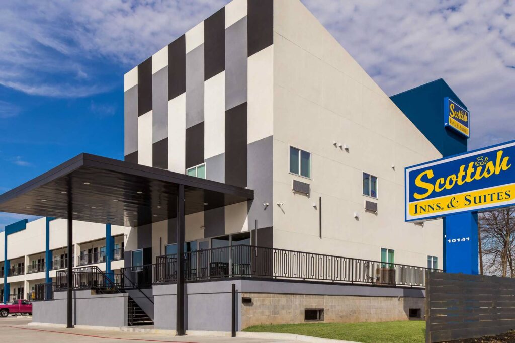 Hotel entrance with canopy, two story building with covered walkways , exterior guest room entrances and stairways, parking spaces, brand signage