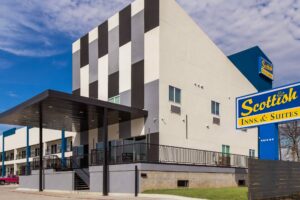 Hotel entrance with canopy, two story building with covered walkways , exterior guest room entrances and stairways, parking spaces, brand signage