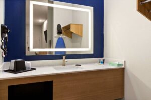 Vanity unit with backlit mirror, hairdryer, bathroom amenities, ice bucket