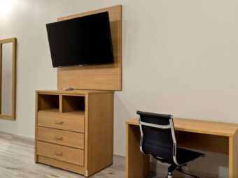 Full length mirror, wooden drawer unit, wall mounted TV, desk with office chair, tiled flooring