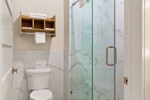 Toilet, shelves with towels, shower with glass sliding doors
