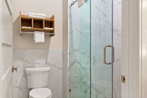 Toilet, shelves with towels, shower with glass sliding doors