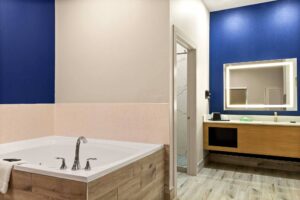 Spa tub. vanity unit, backlit mirror. doorway to bathroom, tiled flooring