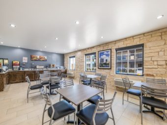 Tables and chairs, breakfast display counter with cereal dispensers, juice dispenser, waffle maker, tiled flooring