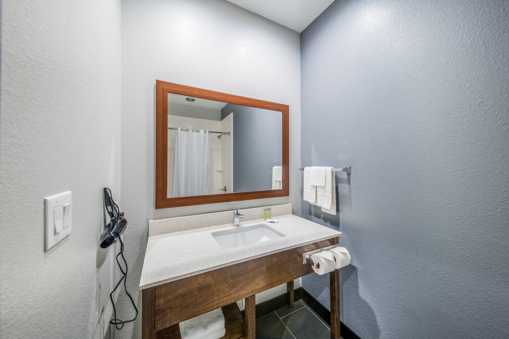 Vanity unit, bathroom amenities, towel rail with towels, mirror, hairdryer, tiled flooring
