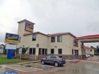 Hotel entrance with drive through canopy, brand signage, two story building, parking spaces