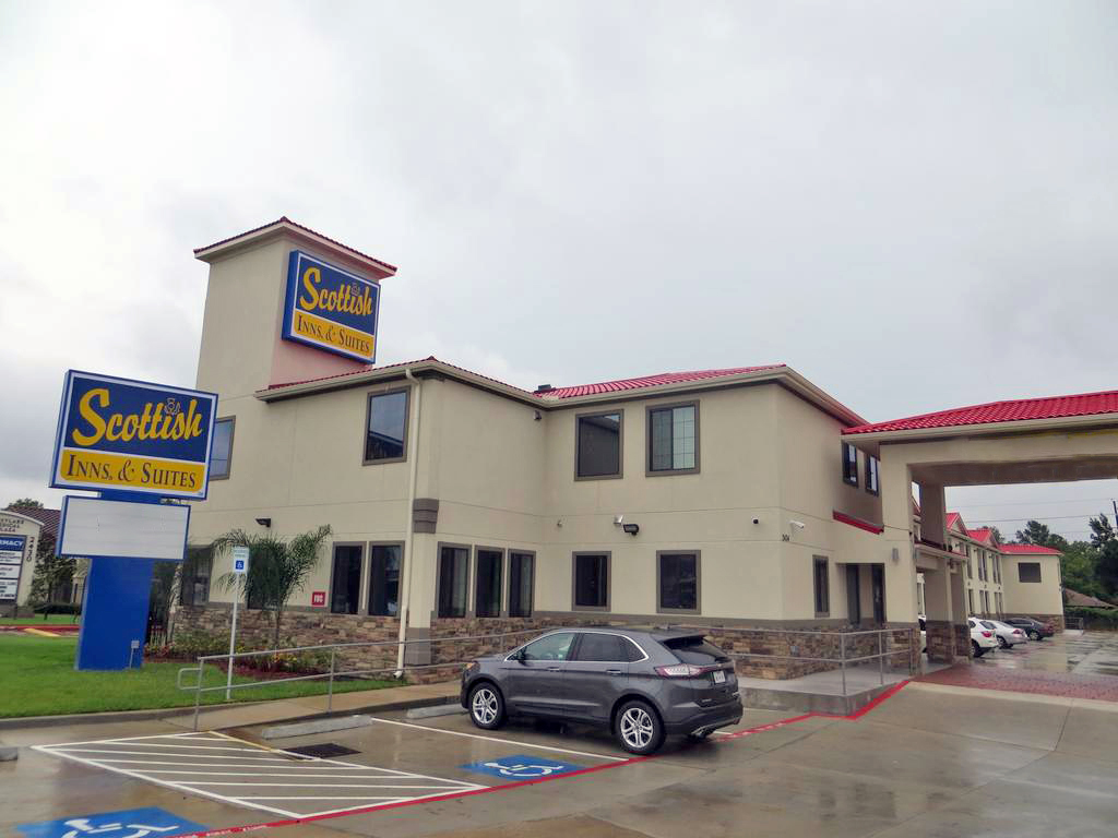 Hotel entrance with drive through canopy, brand signage, two story building, parking spaces