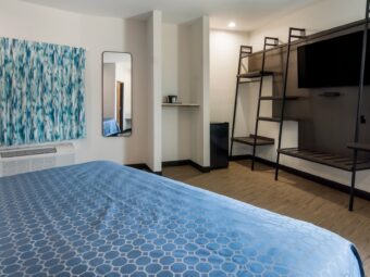 King bed, full length mirror, alcove with shelp, fridge, wall shelves with flatscreen TV, carpet flooring