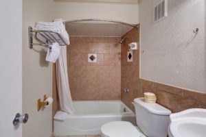 Shower tub with shower curtain, towel shelf with towels, toilet, sink